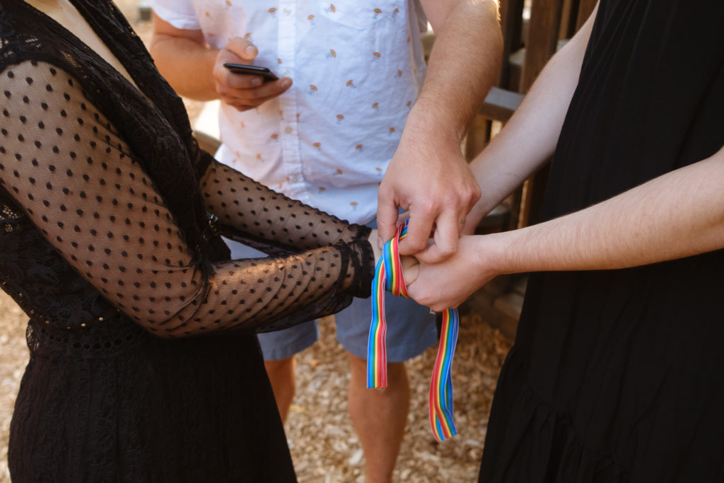 Queer couple performing a handfasting ceremony during their summer elopement in Orange City Iowa.