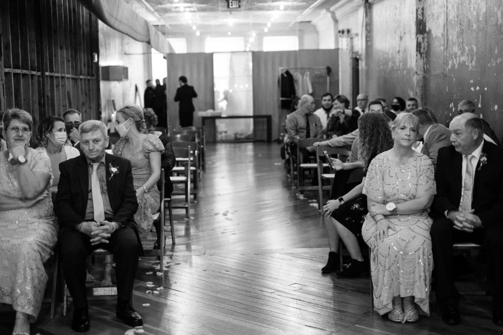 View of the wedding guests from the front of the aisle at the ceremony. The couples parents are seated in the front row. Teachout Building in Des Moines Iowa