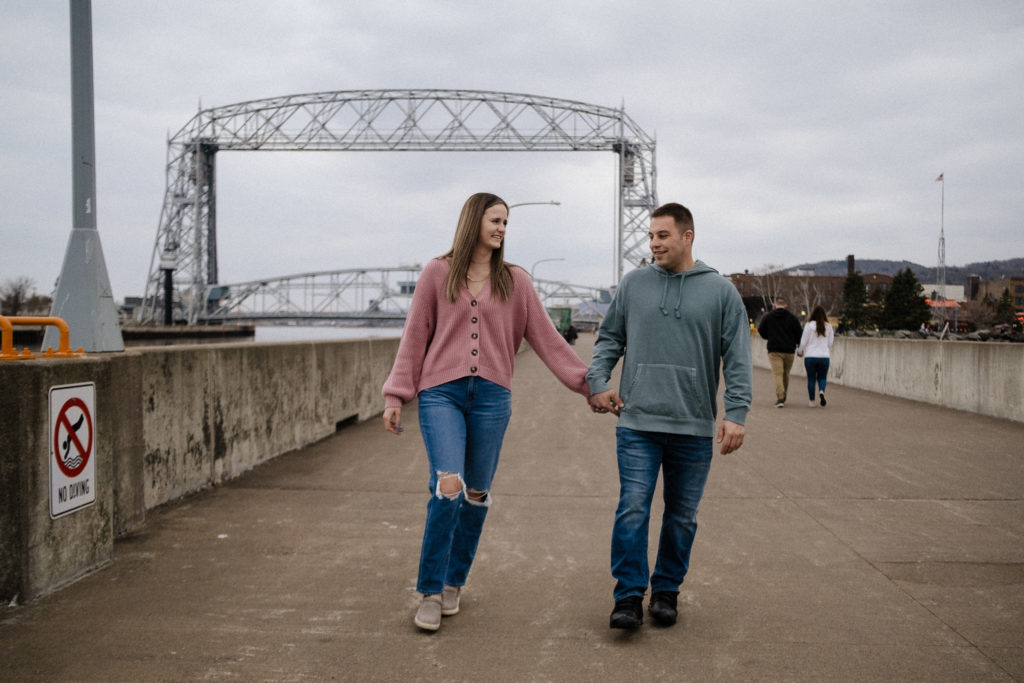 Couple holding hands and walking away from the lift bridge in Canal Park
