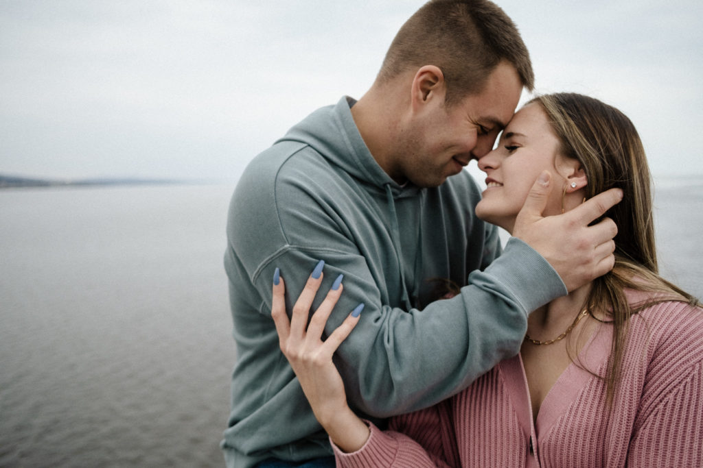 A sweet embrace with foreheads touching with the cloudy skies in the background.