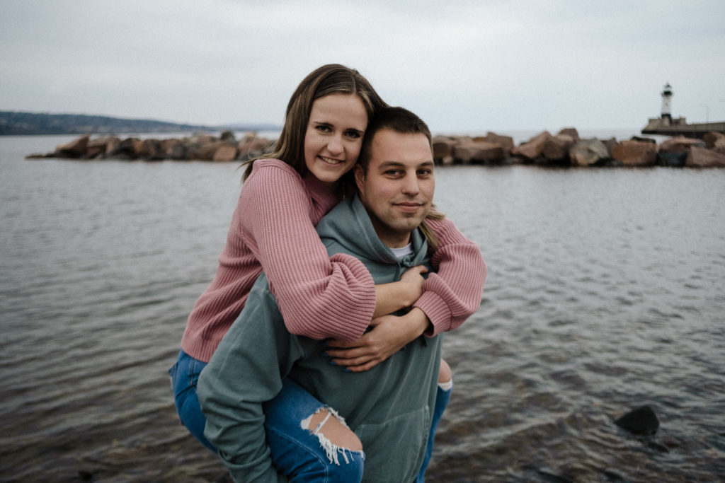 Couple in piggyback pose in front of the lakeside