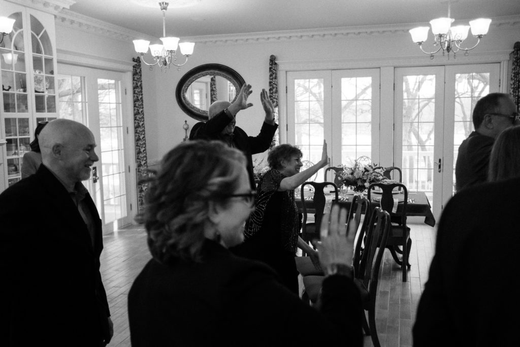 Black and white image of the bride and groom's family waving to the wedding guests who attended via Zoom video.