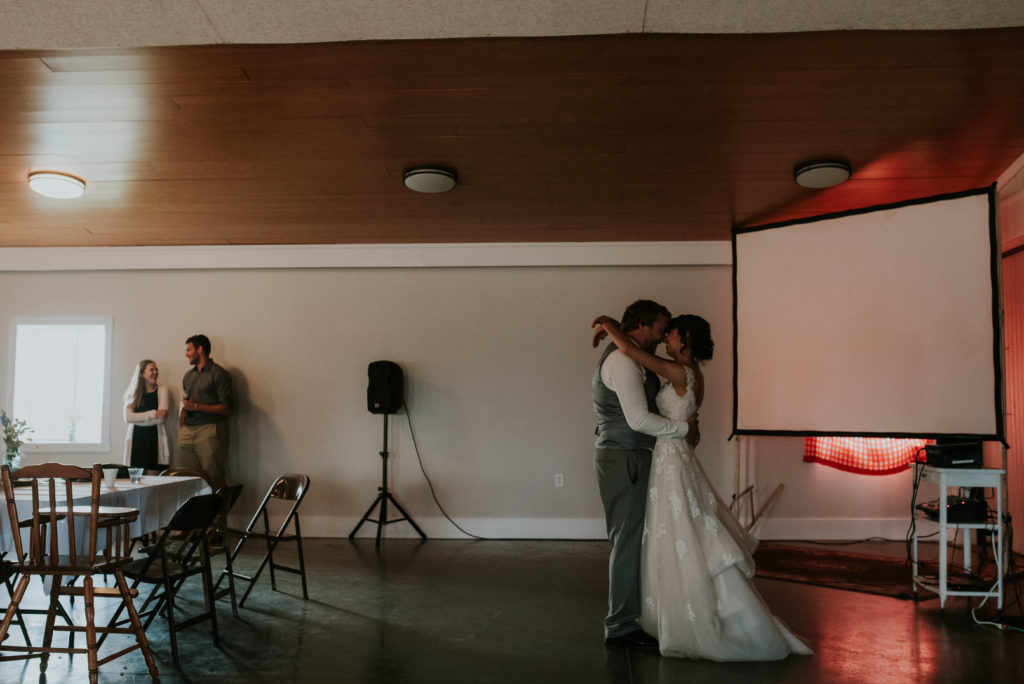 Newlywed couple sharing their first dance in a dimly lit reception hall. 