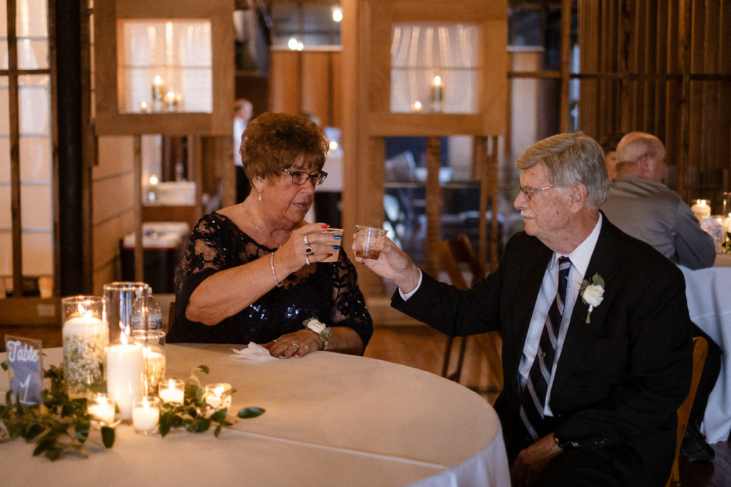 Older couple clinking glasses at the wedding reception in the Teachout Building in Downtown Des Moines, Iowa.