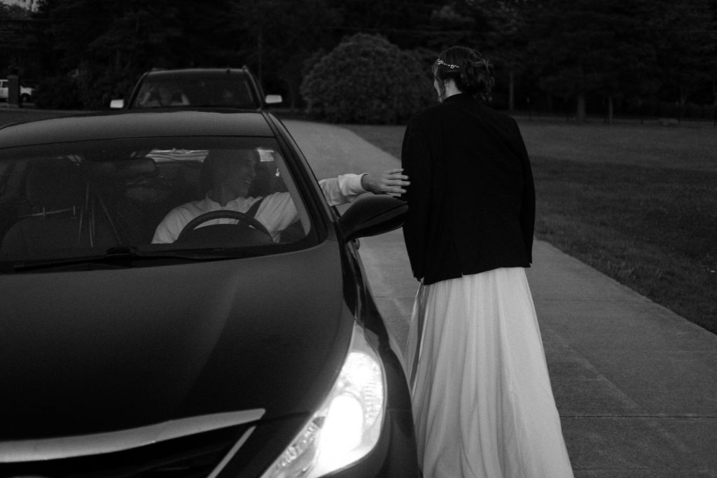 Bride's father extends a hand out the car window to say good bye to his daughter. 