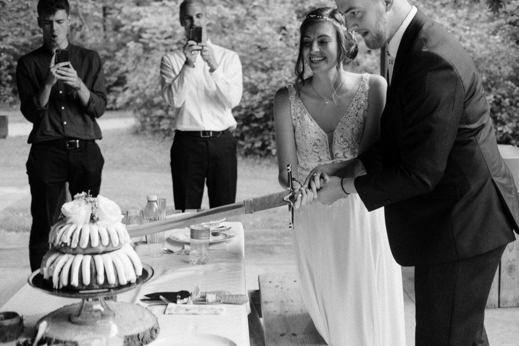 Cutting the wedding cake with a sword. Intimate wedding in Cleveland Ohio.