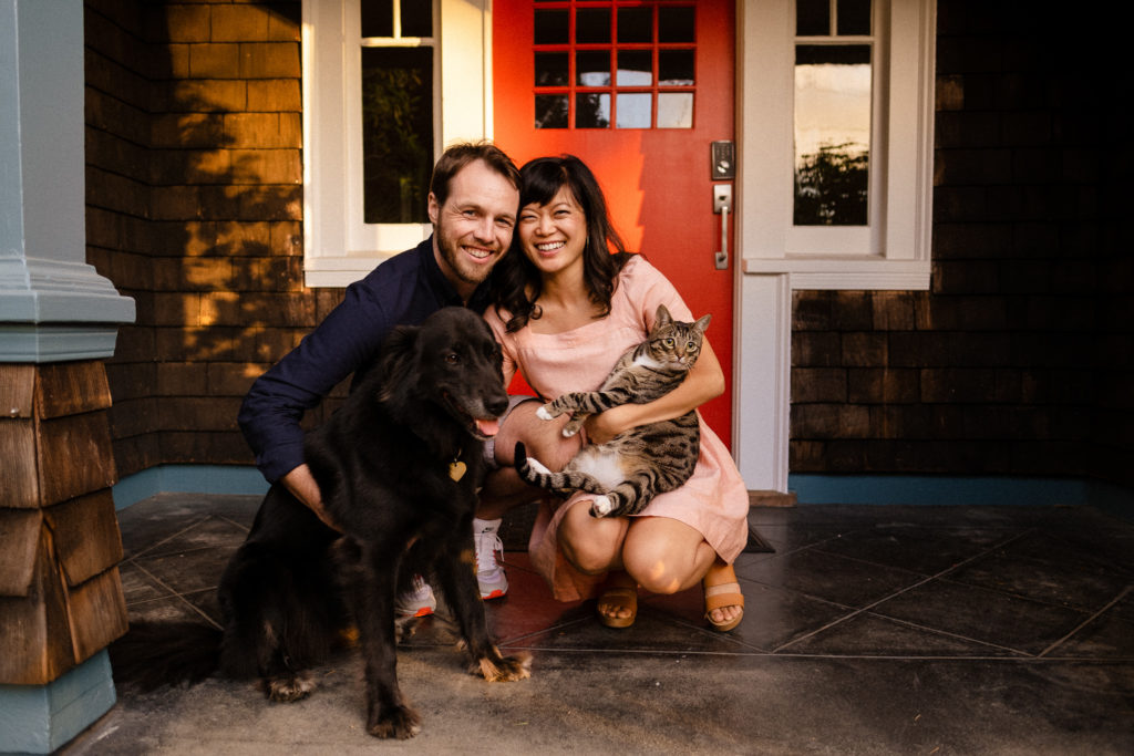 Color image of Steph and Craig kneeling with their pets on the front porch during their engagement session in California.