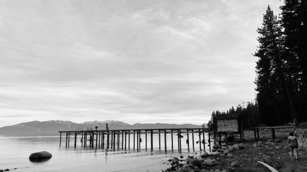 A black and white landscape photo of a dock by Lack Tahoe.
