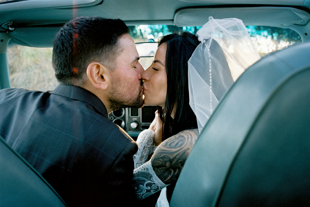 A photo of the bride and groom kissing in the front seat of their vintage camaro from their wedding in Canal Park.