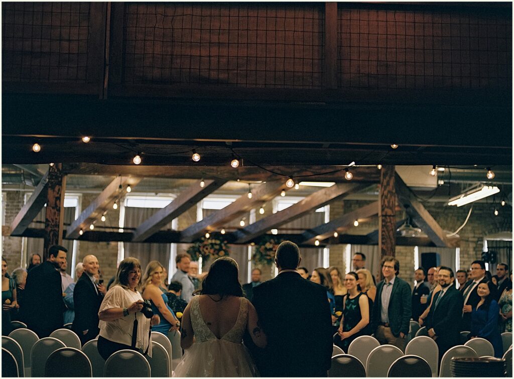 A bride and groom enter a wedding reception at a brewery.