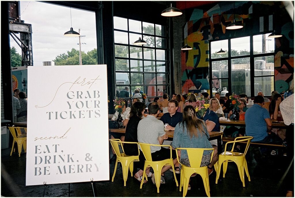 Wedding guests sit at tables drinking beers inside a brewery wedding venue in Minneapolis.
