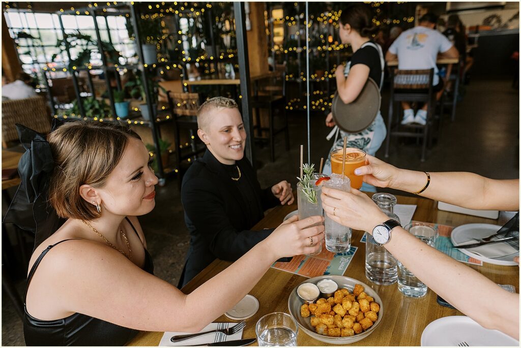 Two marriers clink glasses with friends in their brewery wedding venue.