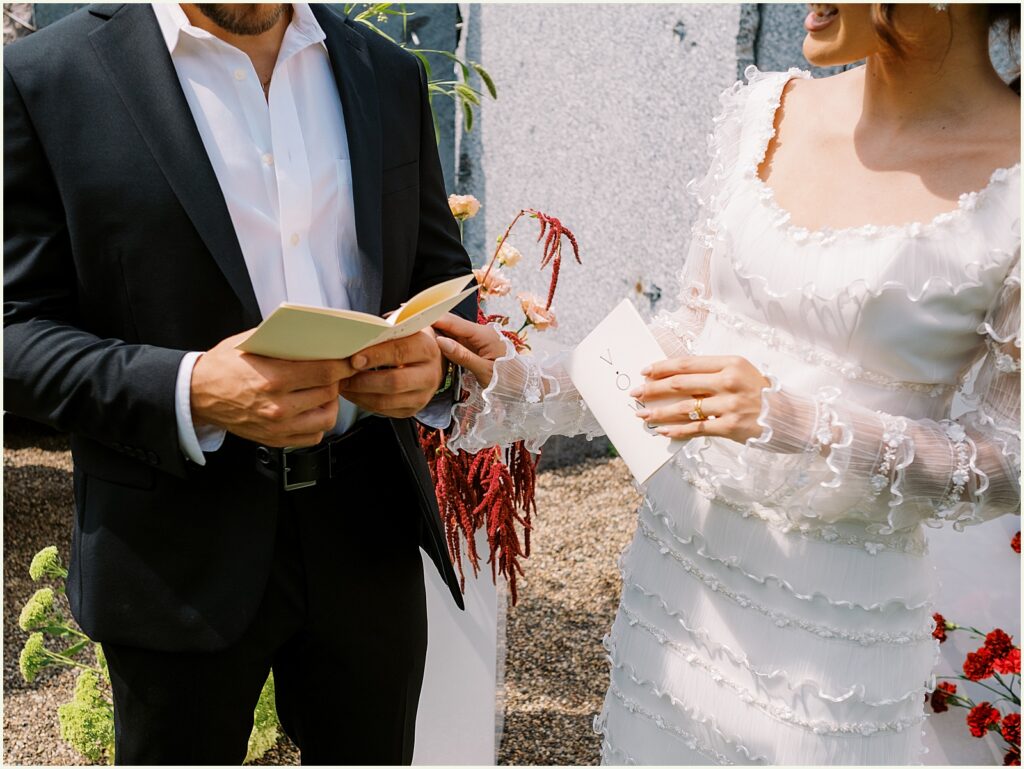 A bride places her hand on a groom's arm while they exchange vows.
