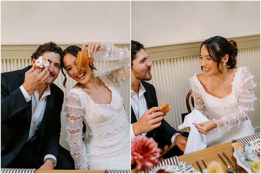 A bride and groom hide behind pastries in a playful pose.