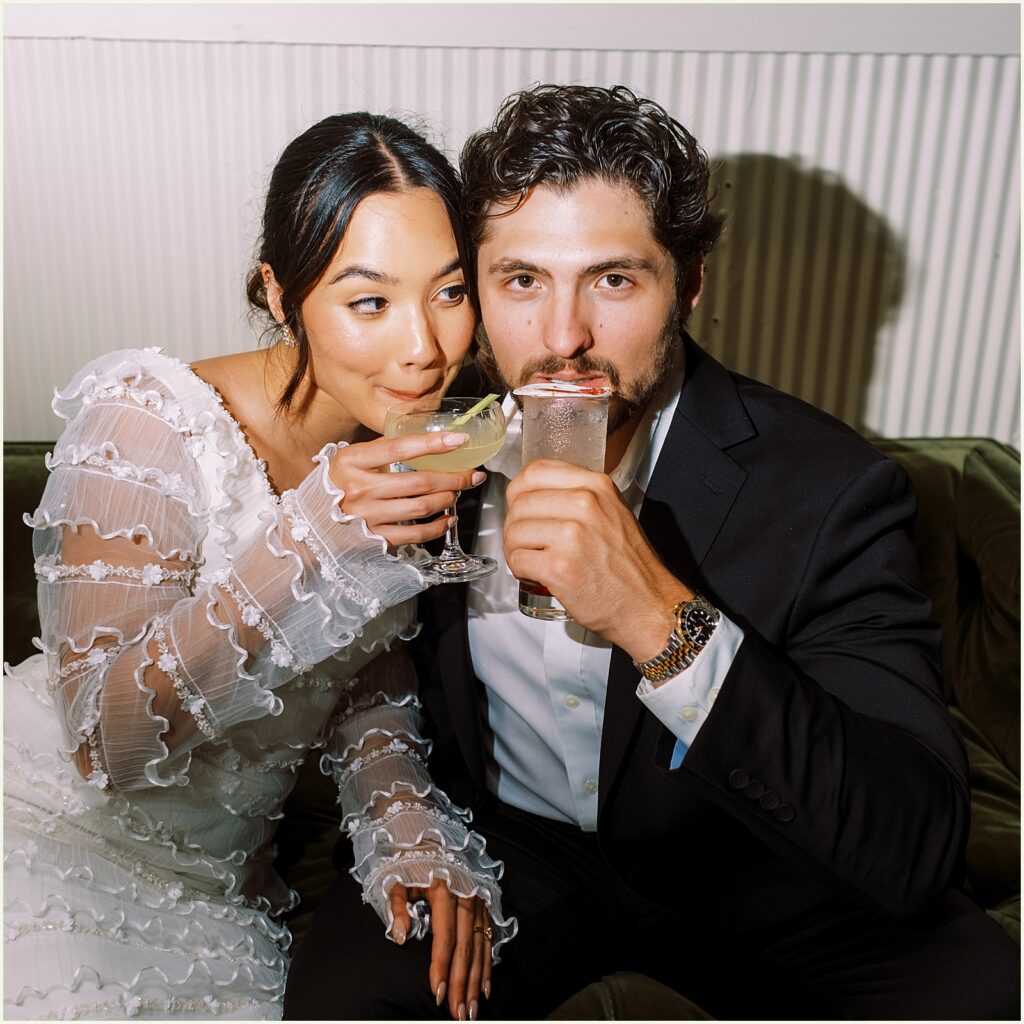 A bride and groom sip cocktails.