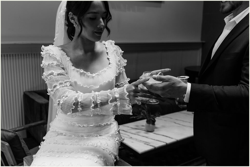 A groom hands a bride a cocktail.