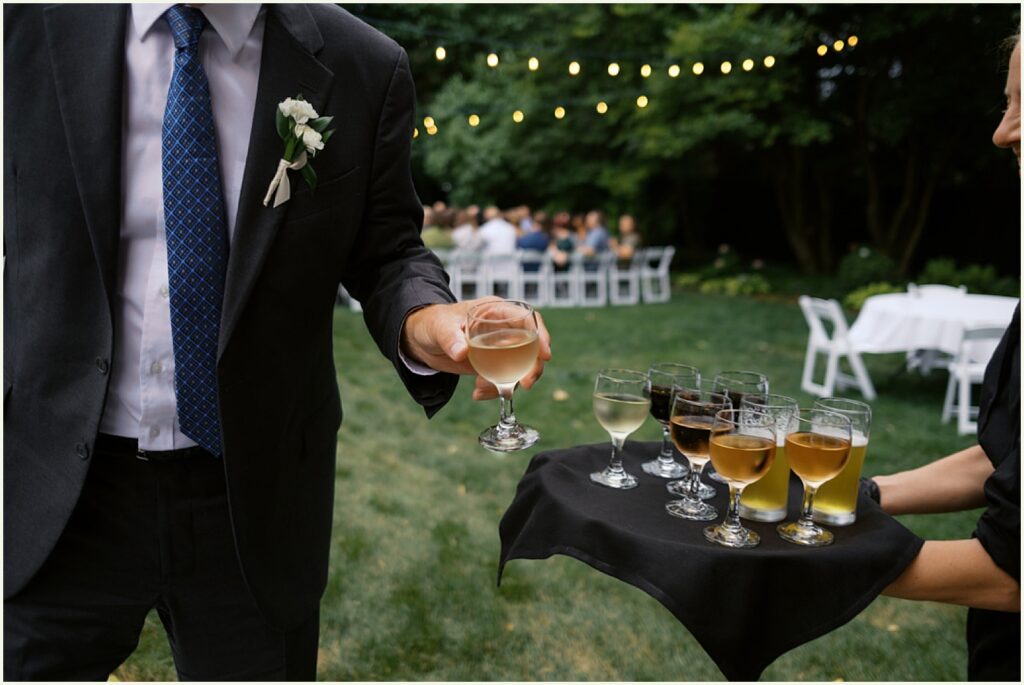 A man in a suit picks up a wine glass from a tray.
