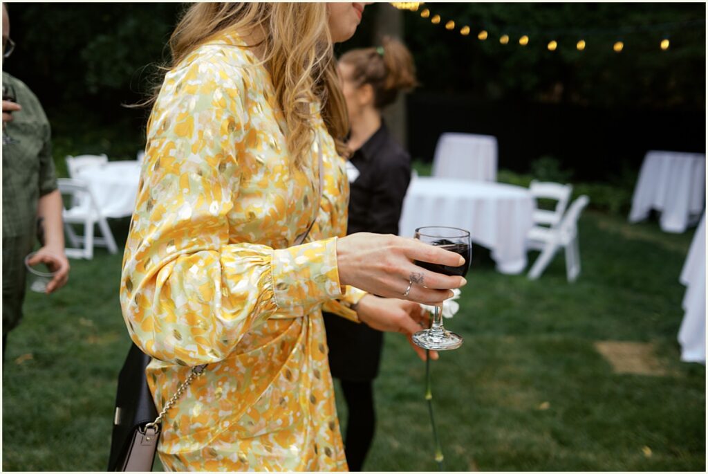 A woman in a yellow dress carries a cocktail glass.